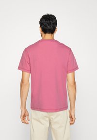 Rosa bomullströja med korta ärmar och rundad halsringning. Slät textur med synlig sömnad och en avslappnad passform.