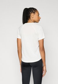 Λευκό κοντομάνικο μπλουζάκι με ραγκλάν μανίκια, κατασκευασμένο από ελαφρύ ύφασμα. Διαθέτει στρογγυλεμένο τελείωμα και διακριτικό λογότυπο στο πίσω μέρος.