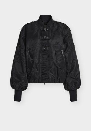 Μαύρο μπουφάν bomber με λεία, γυαλιστερή υφή. Διαθέτει φερμουάρ μπροστά, δύο πλαϊνές τσέπες και τρεις διακοσμητικές αγκράφες στο στήθος.
