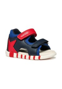 Sandal blu e rosso con tomaia in pelle blu navy, accenti in rete e due cinturini in Velcro. Presenta una suola bianca con strisce rosse e bianche.