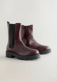 Bocanci de glezna din piele burgundă, cu fermoar lateral, panouri elastice negre contrastante și o talpă robustă din cauciuc negru pentru tracțiune.