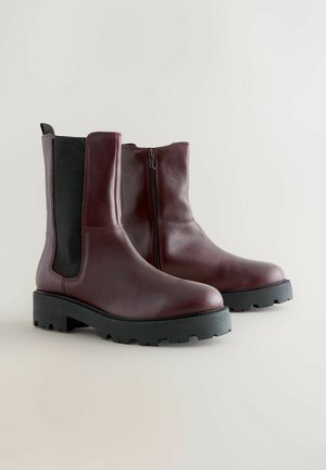 Bordeauxfarbene Leder-Stiefeletten mit einem seitlichen Reißverschluss, kontrastierenden schwarzen elastischen Einsätzen und einer robusten schwarzen Gummisohle für besseren Halt.