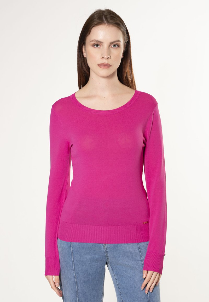 Fuchsia langer Pullover mit Rundhalsausschnitt, gerippten Bündchen und schlanker Passform. Weiche Textur. Kombiniert mit Denim-Hosen.