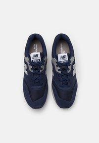 Navy blue sneakers with mesh and suede materials, featuring a gray accent, branded tongue, and a textured sole for grip.