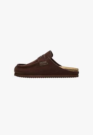 Hnedá semišová mokasína na slip-on so štruktúrovanou plochou podrážkou a prešitým remienkom cez hornú časť.