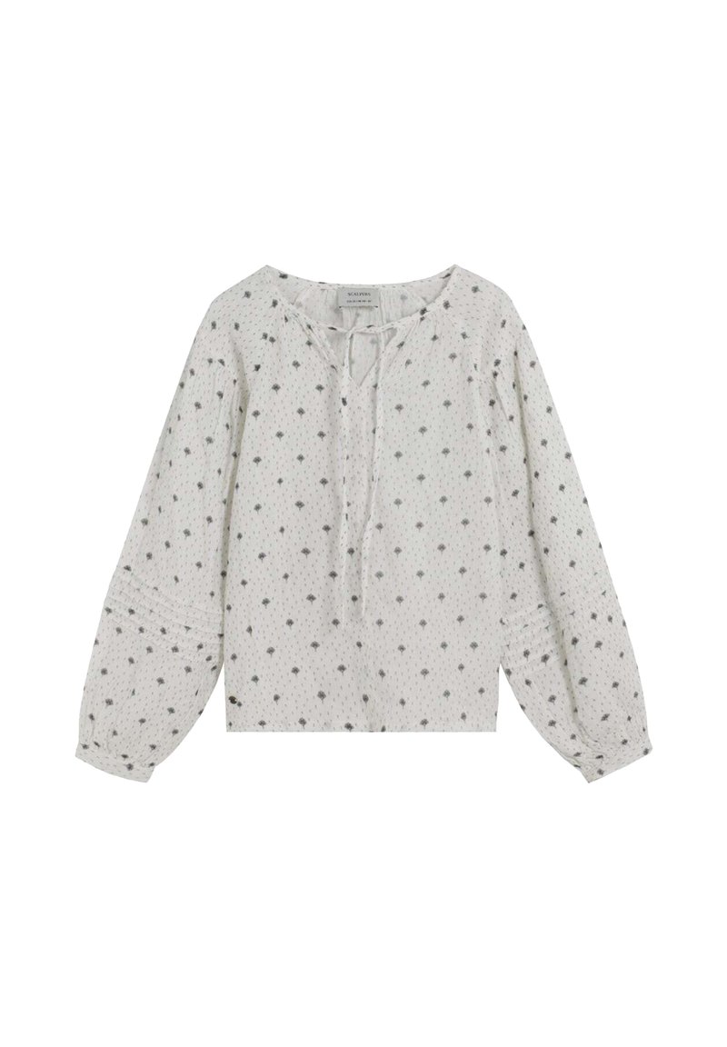 Blusa blanca de manga larga con cuello redondo, que presenta un detalle de lazo y un tejido texturizado, adornada con pequeños patrones florales grises.