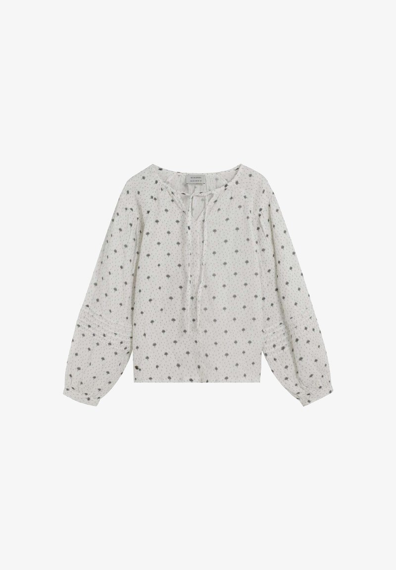 Blusa blanca de manga larga con cuello redondo, que presenta un detalle de lazo y un tejido texturizado, adornada con pequeños patrones florales grises.