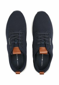 Zapatillas de malla azul marino con suela blanca, con detalles en cuero marrón, cordones redondos y marca en el lateral y la plantilla.