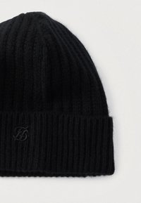 Gorro de punto negro con textura acanalada y puño enrollado. Presenta un logo bordado sutil en la parte frontal. Material suave de lana.