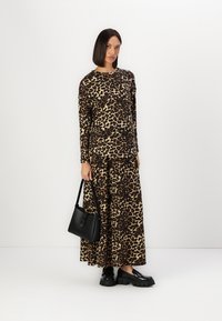Bluza z dolgimi rokavi v leopardjem vzorcu in maxi krilo iz mehkega materiala; v kompletu z črno torbico in črnimi platform čevlji.