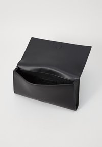 Czarna skórzana torebka kopertówka o gładkiej fakturze, z klapką i prostą kieszonką wewnątrz. Bez widocznych elementów metalowych ani wzorów.