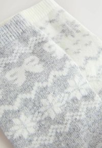 Calcetines de lana que presentan un patrón de copos de nieve en gris y blanco, con una textura suave y un puño acanalado en la parte superior.