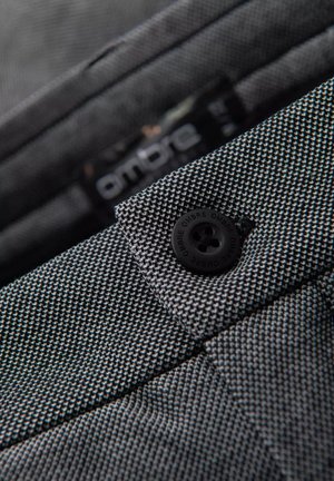 Tela de patrón en blanco y negro con un tejido texturizado, que presenta un botón de plástico negro y una etiqueta visible con la marca "Ombre".