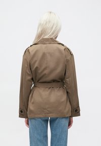 Brown belted trench coat with a classic collar, long sleeves, and button accents. The fabric appears smooth with a matte finish.