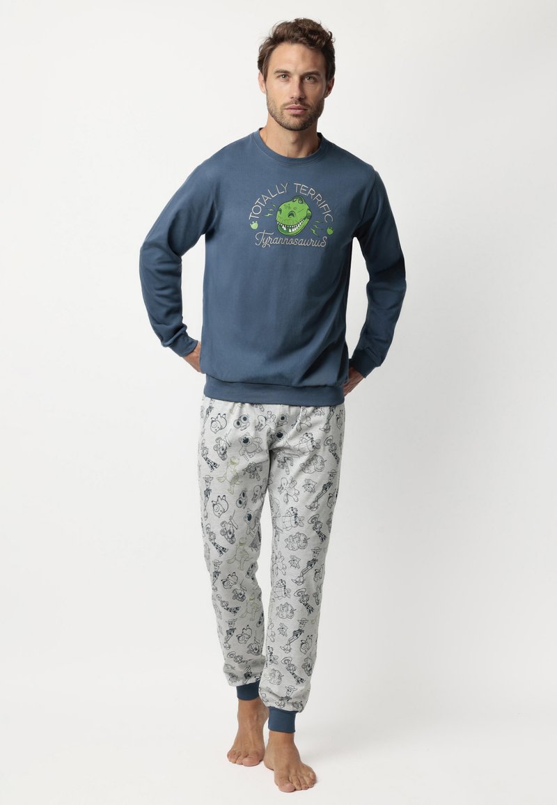 Sudadera azul con un gráfico de dinosaurio verde y diseño de texto, combinada con pantalones de pijama gris claro que presentan varios patrones caricaturescos.
