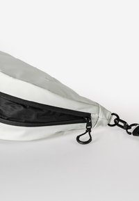 Grau-weiße Schultertasche aus weichem Material, mit einem Reißverschluss, schwarzen Akzenten und einem abnehmbaren Tragegurt mit Hardwaredetails.