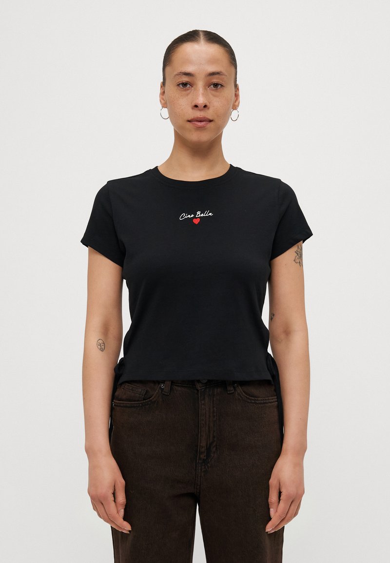Zwarte katoenen t-shirt met korte mouwen, ronde hals, voorzien van geborduurde witte en rode tekst "Ciao Bella" en een klein rood hartdetail.