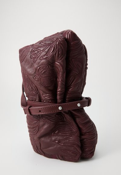 Burgundy leather bag with embossed floral patterns, cinched design, and a matching belt strap featuring silver hardware accents.