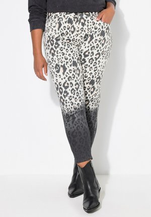 Luipaardprint legging in een verloop van crème naar zwart aan de zoom, met een soepele textuur; gecombineerd met zwarte enkellaarsjes.