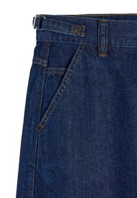 Granatowe dżinsy o prostym kroju, z kontrastowym pomarańczowym szwem, szlufkami na pasek i kieszeniami bocznymi.