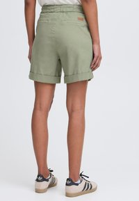 Grønne shorts i bomullsmiks med rullekanter og elastisk midje. Med baklommer og en liten merke-patch på midjen.