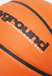 Balón de baloncesto naranja con una superficie texturizada, que presenta acentos y una marca negra que dice "balón de juego al aire libre playground".