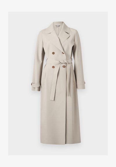 Μακρύ μπεζ διπλόμπουτο παλτό τύπου τρανς με φαρδιές πέτσες, καφέ κουμπιά, ζώνη στη μέση και μανσέτες με κουμπιά.