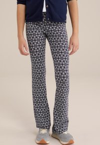 Tamsiai mėlynų raštų kelnės su baltos spalvos gėlių dizainu. Medžiaga yra minkšta, elastinga, su išplatintu siluetu, derinama su pilkais sportbačiais.