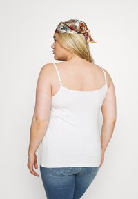 Witte mouwloze tanktop gemaakt van gladde stof, met verstelbare schouderbanden. Draag het met blauwe jeans, wat een eenvoudige uitstraling geeft.