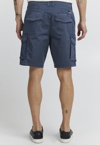 Marineblå cargo shorts med to store sidelommer, to baklommer og beltehemper. Laget av lett stoff med en glatt tekstur.