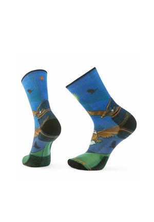 Bunte Socken mit einer blauen und grünen Landschaft, die Vögel und Berge zeigt. Hergestellt aus Stoff mit verstärktem schwarzen Fersen- und Fußbereich.