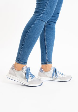 Scarpe da ginnastica argento e blu con una texture liscia, forma arrotondata e lacci. Presentano una parte superiore metallica lucida e una suola bianca.