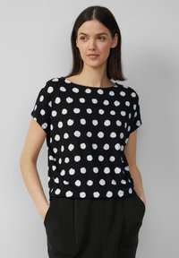 Zwart T-shirt met korte mouwen en een ronde hals, voorzien van een wit stippenpatroon, gemaakt van zachte stof, gecombineerd met zwarte broek.