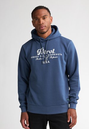 Felpa con cappuccio blu navy realizzata in tessuto morbido, con stampa grafica frontale in bianco. Include un cappuccio con cordino e polsini e fondo a costine.