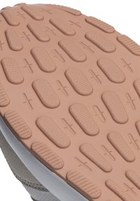 Schuhsohle aus strukturiertem Gummi in Beige und Grau. Auffällige erhabene Muster für besseren Halt, mit kreisförmigen und ovalen Formen über die Oberfläche verteilt.