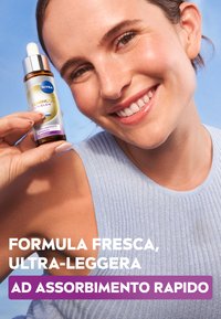 Siero NIVEA Luminous Skin Glow in una bottiglia di vetro con contagocce, con etichetta argento e blu e un accento viola. Texture liscia.