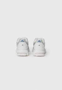 White athletic shoes featuring a mesh and synthetic upper, silver accents, blue logo at the heel, and a cushioned white sole.