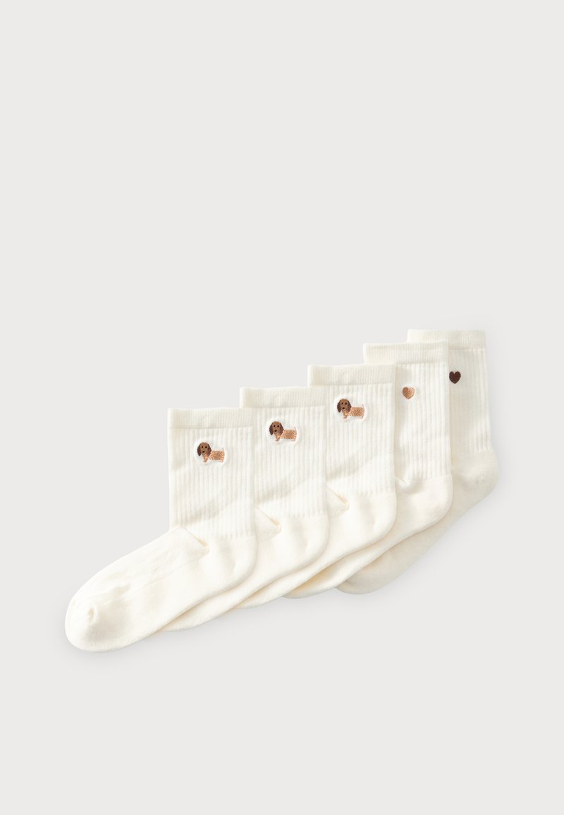 Cinq paires de chaussettes blanches côtelées avec de petits motifs brodés de chiens sur trois paires et des motifs en forme de cœur sur deux paires, disposées en éventail.