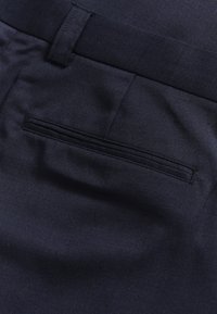 Granatowe spodnie w kolorze navy z gładką teksturą, standardowym wzornictwem kieszeni oraz starannie wykończonym pasem. Tkanina wydaje się być trwała.