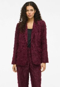 Burgundský texturovaný oblek s třepením; přiléhav�ý blazer s klopovými límci a ladícími kalhotami, doplněný černým topem.