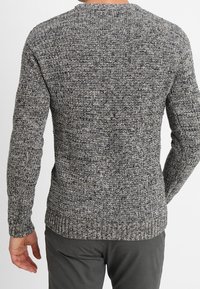 Šedý pletený svetr s texturovaným vzorem, dlouhými rukávy a žebrovaným lemem, zobrazený zezadu s kulatým výstřihem.