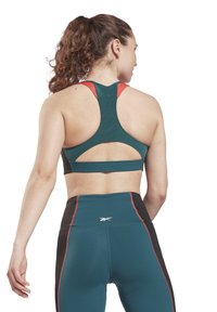 Tirkizni sportski crop top s crvenim detaljima, s dizajnom racerback i izrezom na leđima, u kombinaciji s crnim tajicama visokog struka.