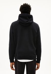 Zwarte hoodie met kangoeroezak, ribgebreide manchetten en zoom. Zacht materiaal, zichtbare naden en een relaxte pasvorm.