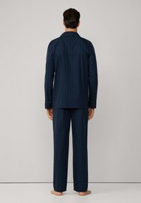 Conjunto de pijama a cuadros en navy y verde que incluye una camisa de botones con cuello y pantalones holgados a juego, fabricado en una tela suave y con detalles en ribete blanco.