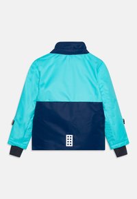 Farbig unterteilte Jacke in Blau und Marine, mit hohem Kragen, Reißverschlussärmeln und einem einfarbigen Rücken mit einer strukturierten Patschendetail.