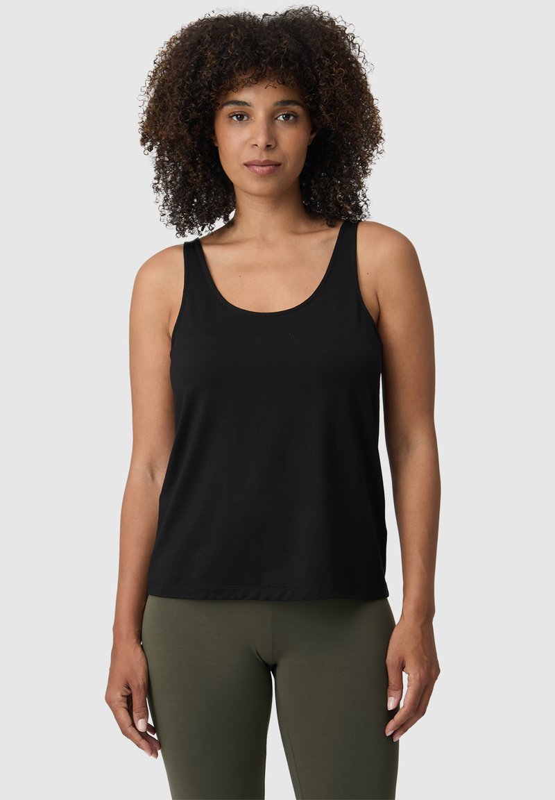 Top senza maniche nero realizzato in tessuto morbido e traspirante, con scollatura rotonda e vestibilità ampia, abbinato a leggings verde oliva.