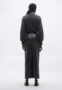 Hall hall villane kampsun, millel on puhvis varrukad, kombineeritud musta nahast maxiseelikuga, millel on tagumine lõhik ja liibuv talje. Välimuse lõpetavad mustad kingad.