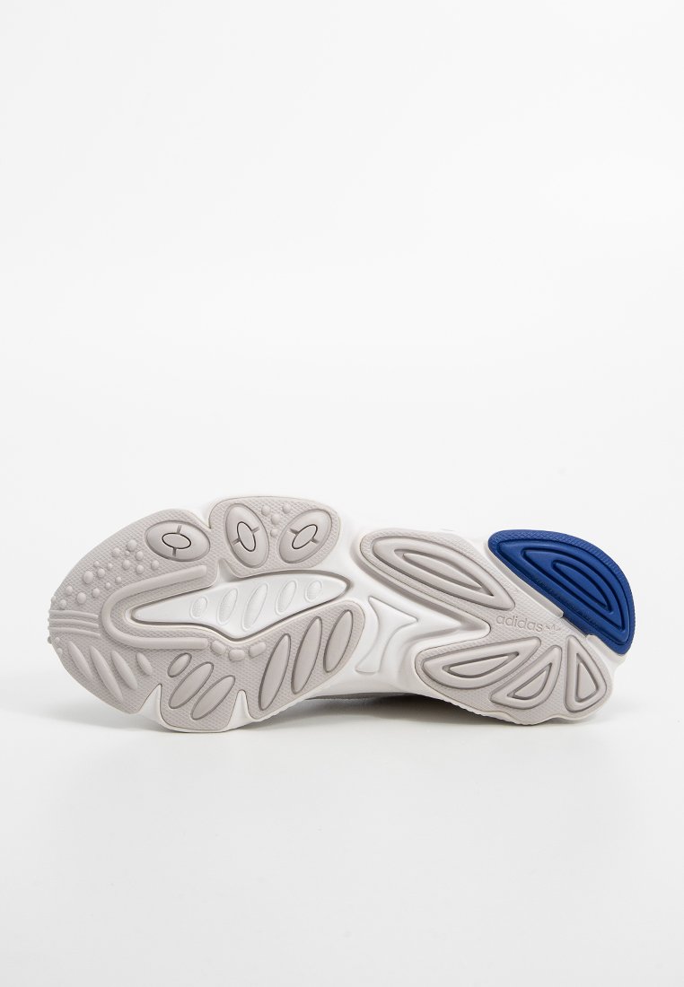 Suela de zapato atlético blanca con patrones texturizados. Incluye un acento azul y ranuras de diferentes tamaños para tracción. Material de goma ligero.