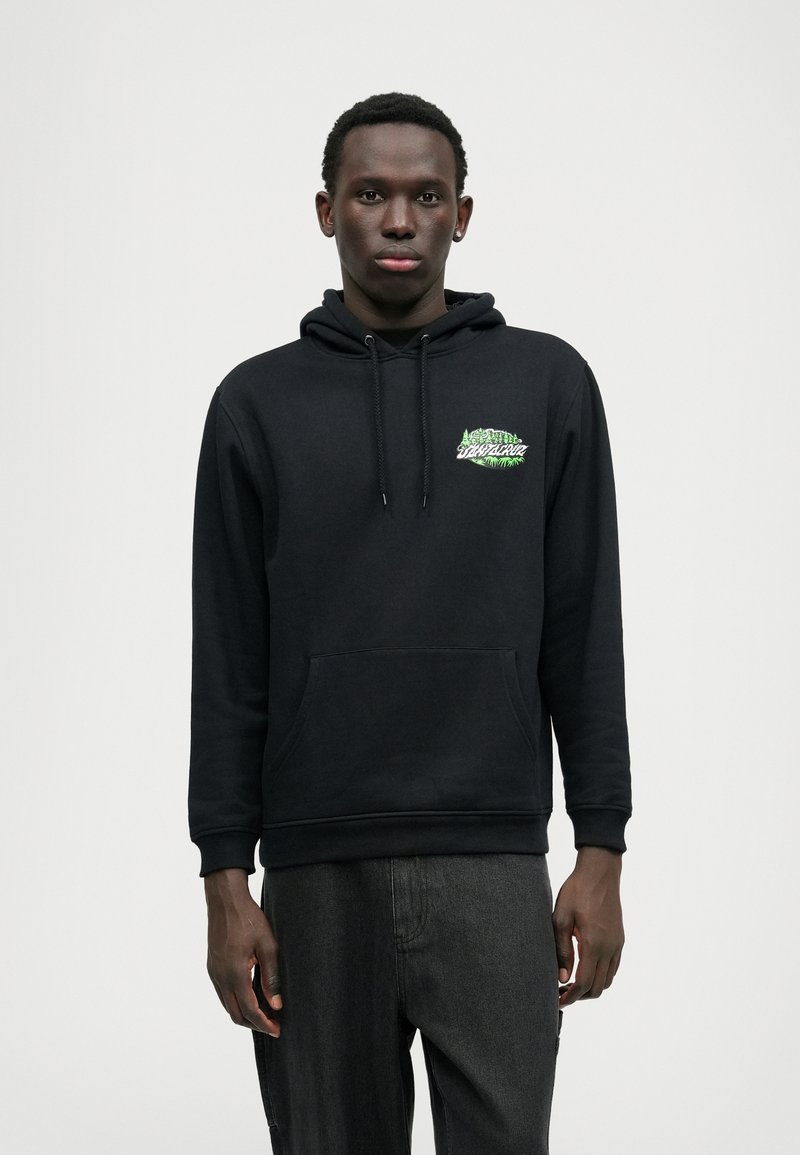 Hanorac negru cu buzunar frontal tip kangaroo, glugă cu șnur și accente grafice verzi pe piept. Țesătura pare moale, cu o croială clasică.