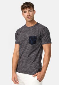 Camiseta gris de manga corta y textura con un bolsillo de estampado azul. Cuenta con un cuello redondo y un corte relajado.